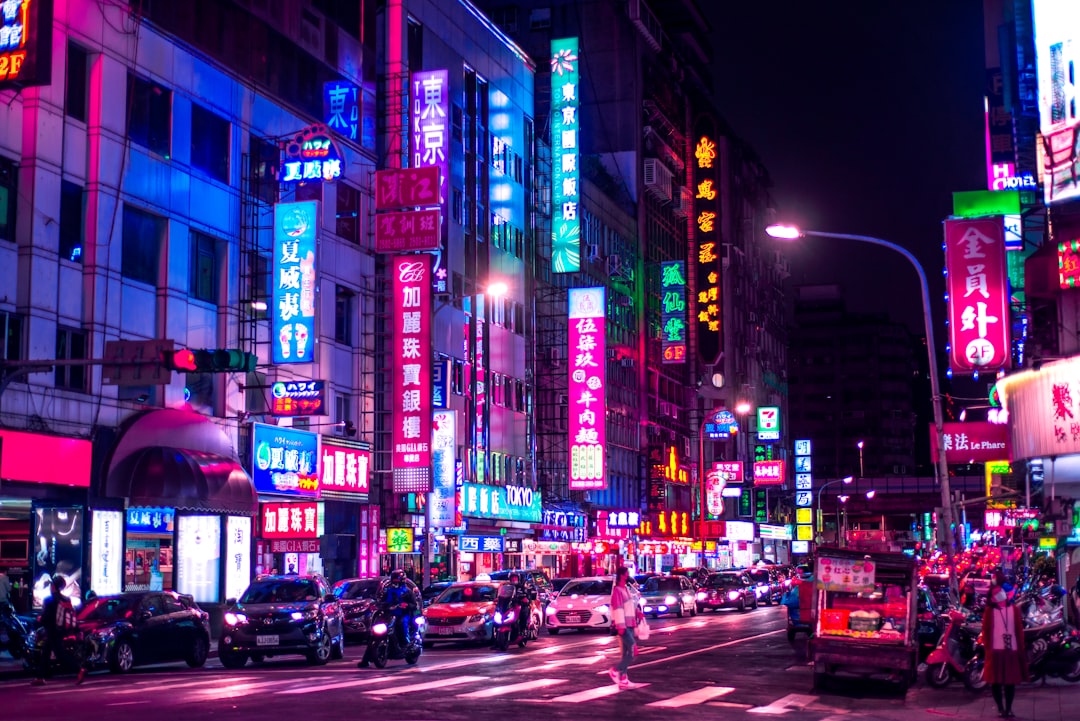 cars on road in between high rise buildings during night time