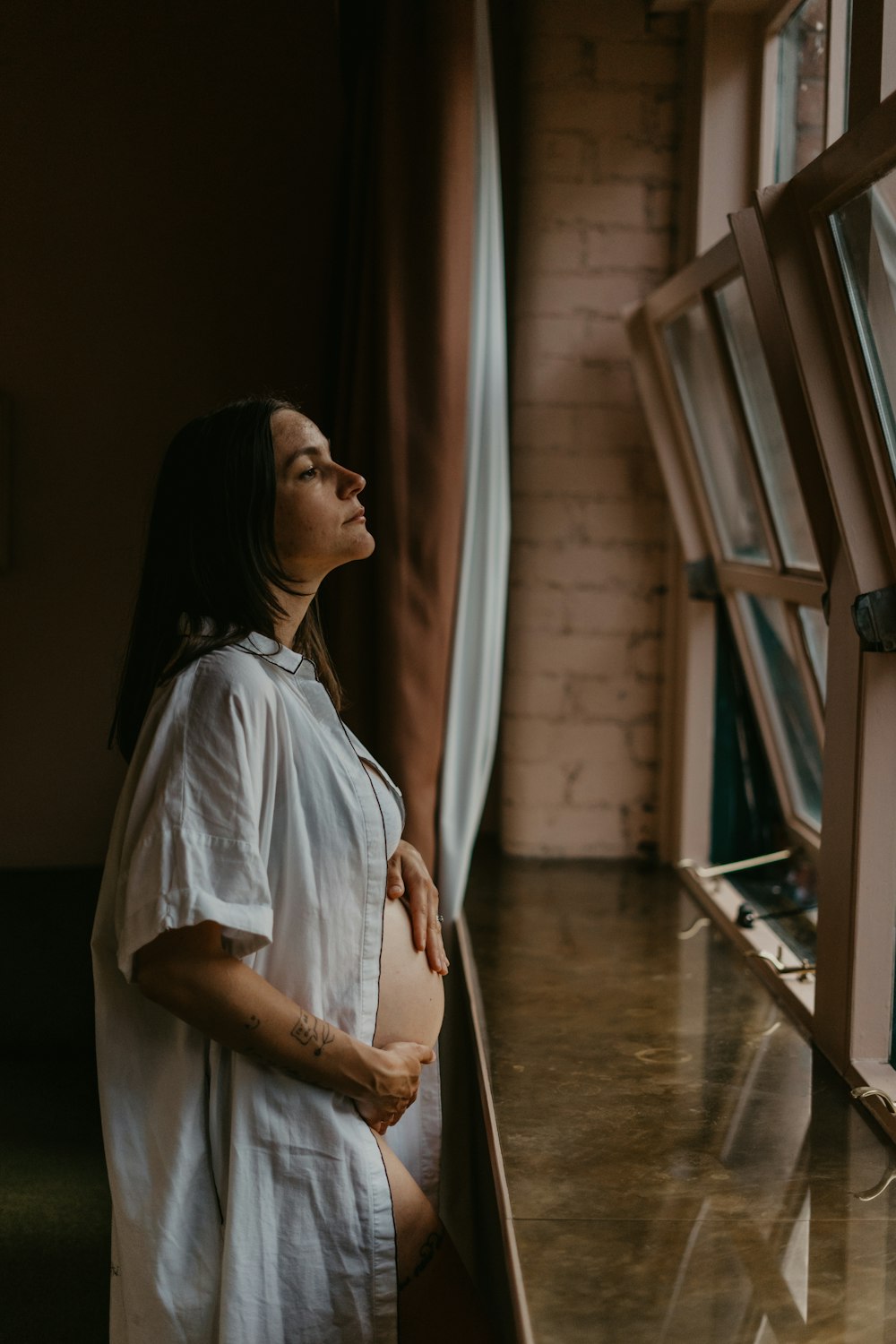 woman in white shirt standing near window