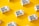 White cartons labeled 'Boxed Water Is Better' are scattered across a bright yellow background. The arrangement is neat and visually appealing, with a combination of vertical and horizontal placements creating a pattern.