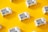 White cartons labeled 'Boxed Water Is Better' are scattered across a bright yellow background. The arrangement is neat and visually appealing, with a combination of vertical and horizontal placements creating a pattern.