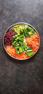 sliced carrots and green vegetable in stainless steel bowl