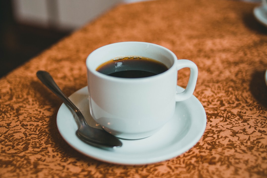 white ceramic cup with black coffee on white ceramic saucer