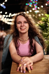 smiling woman in pink tank top sitting on brown wooden bench