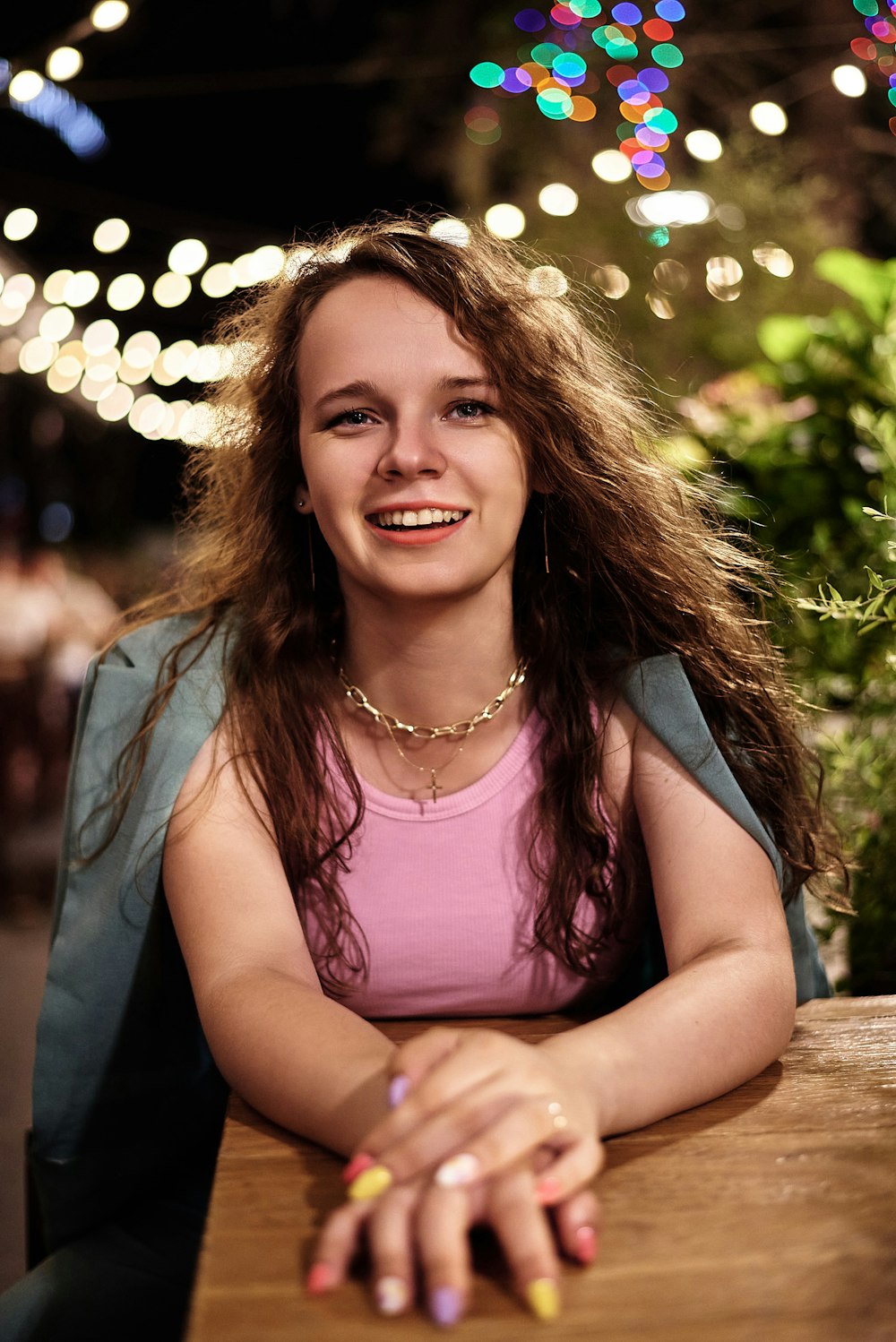 Femme souriante en débardeur rose assise sur un banc en bois brun