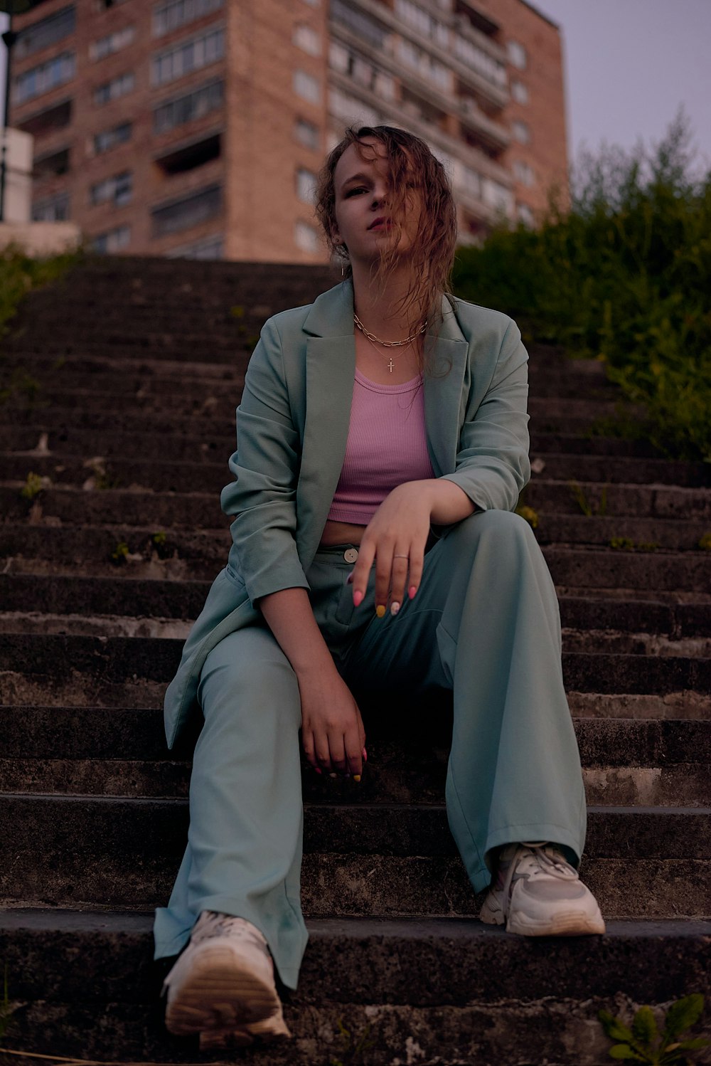woman in gray blazer and blue pants sitting on concrete stairs