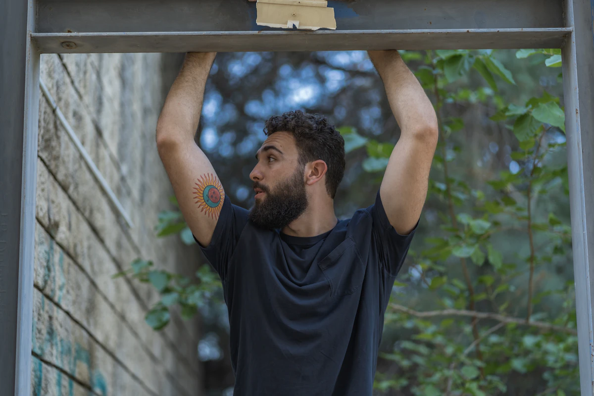 man in black crew neck t-shirt holding on grey metal bar