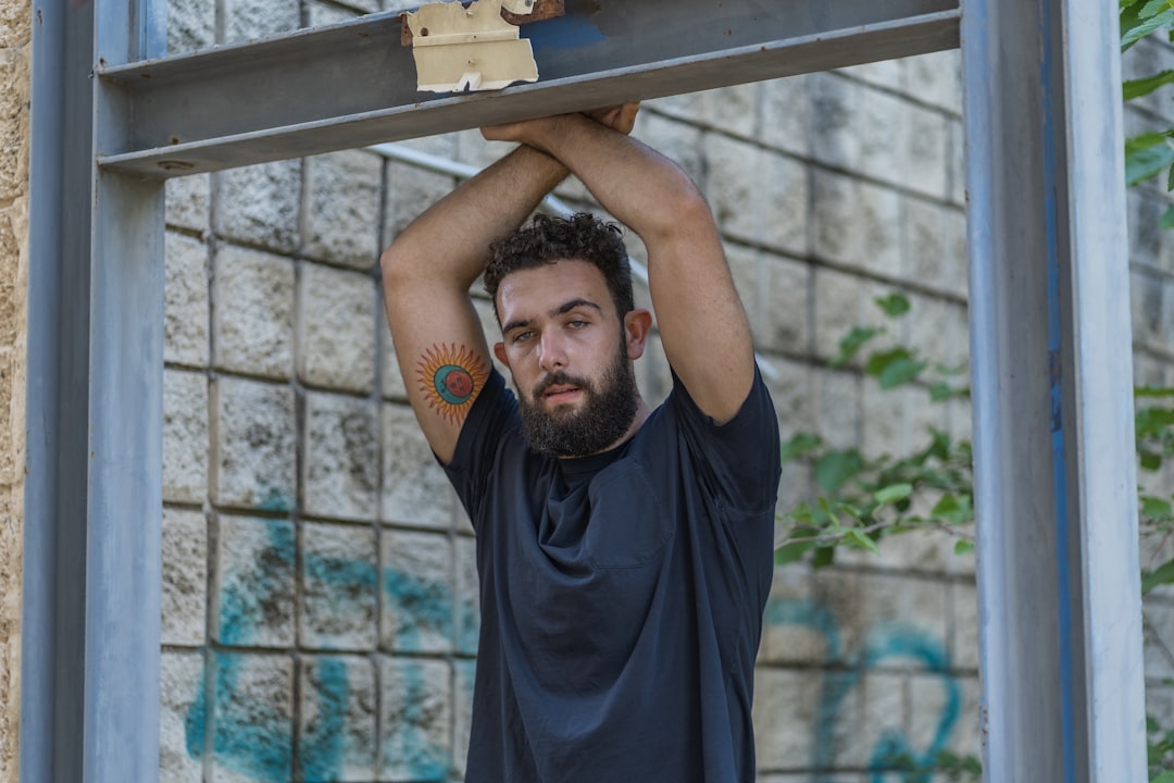 man in black crew neck t-shirt holding on brown wooden frame