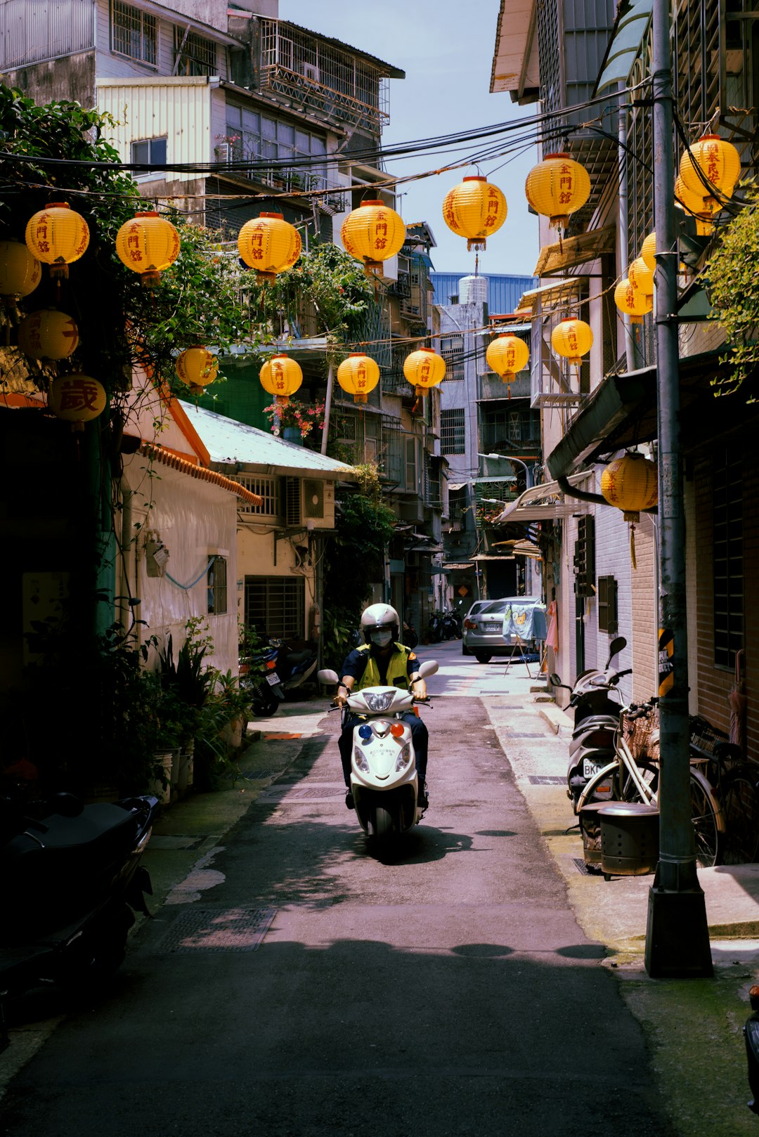 white and black motor scooter parked beside white and yellow lanterns during daytime