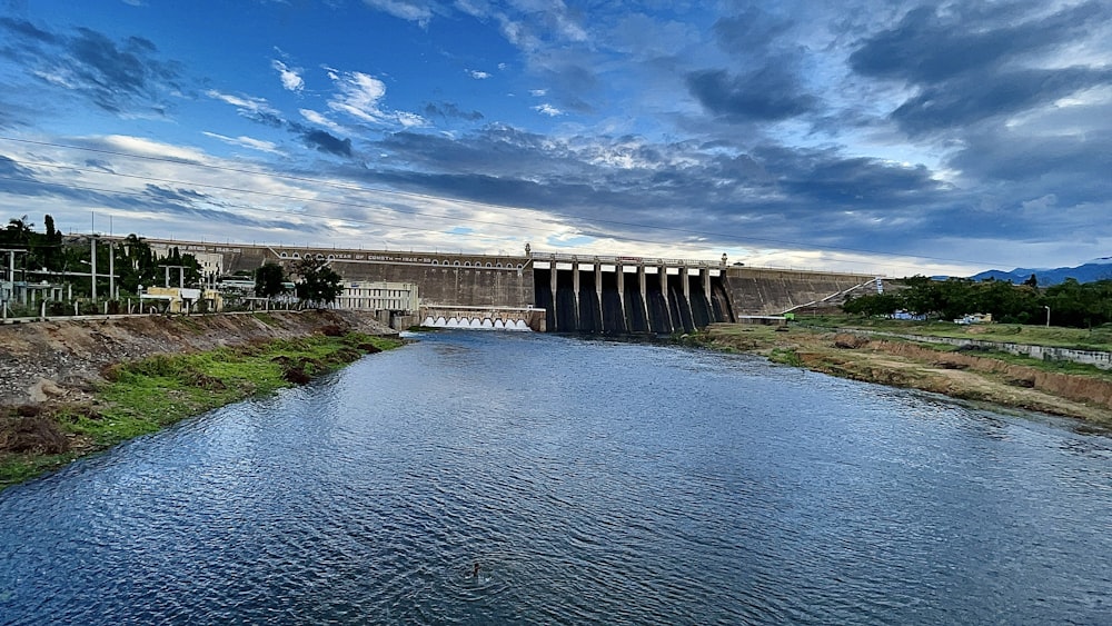 gray concrete bridge over river under blue sky and white clouds during daytime