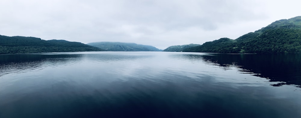 green lake near green mountains during daytime