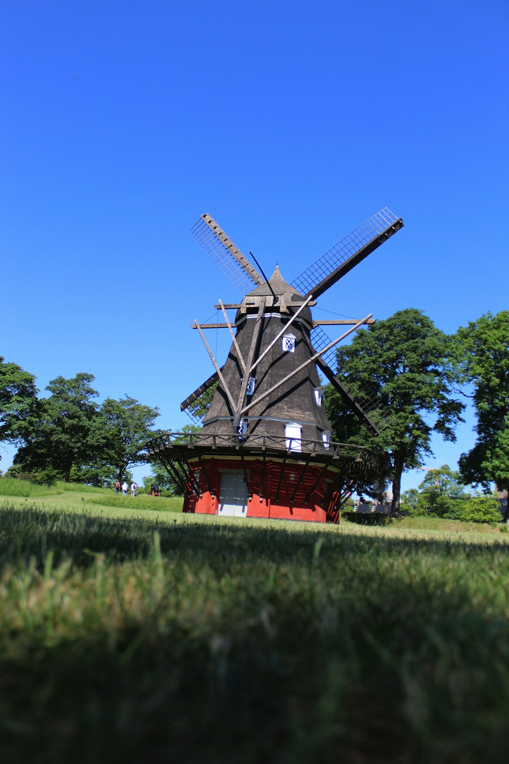 Moulin à vent brun et rouge sur un champ d’herbe verte sous un ciel bleu pendant la journée