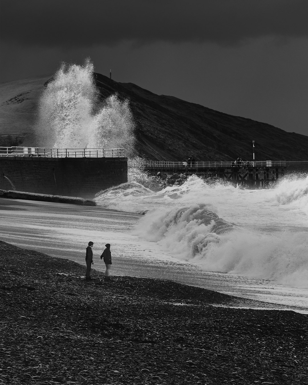 grayscale photo of woman standing on water falls