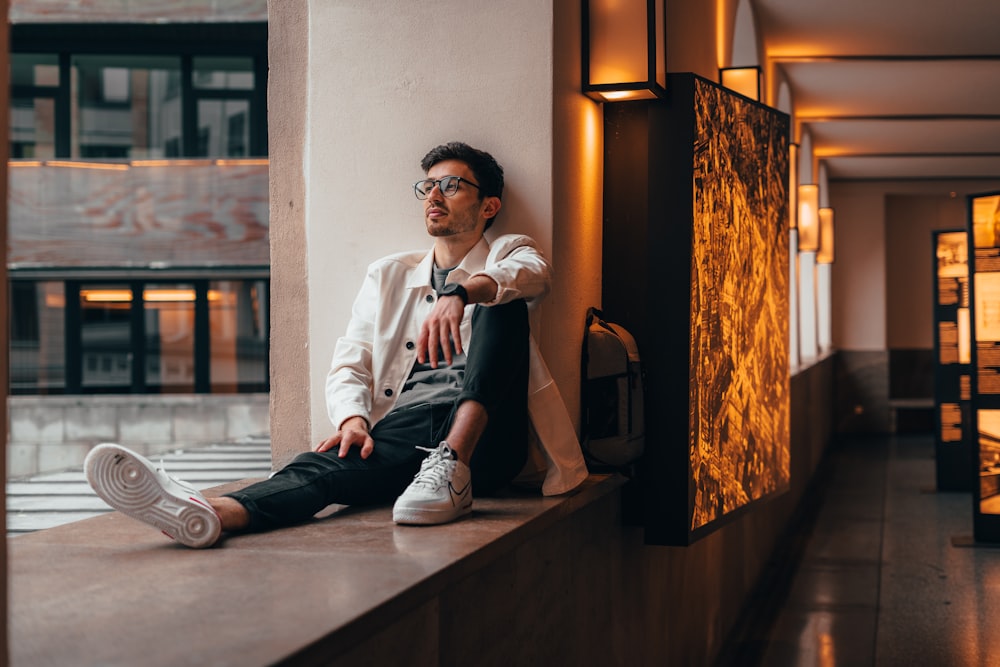 man in white dress shirt and black pants sitting on brown wooden floor