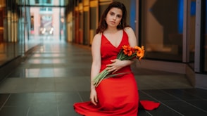 woman in red spaghetti strap dress holding bouquet of flowers