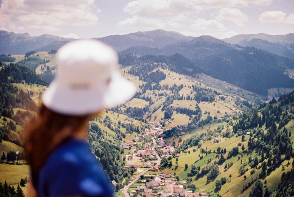 uomo in camicia blu che indossa berretto bianco in piedi sulla montagna durante il giorno