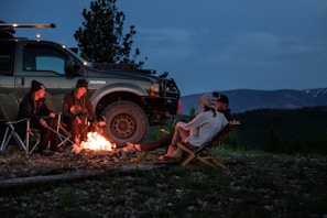 A group of adventurers around an off-road vehicle, sharing stories and gear at sunset
