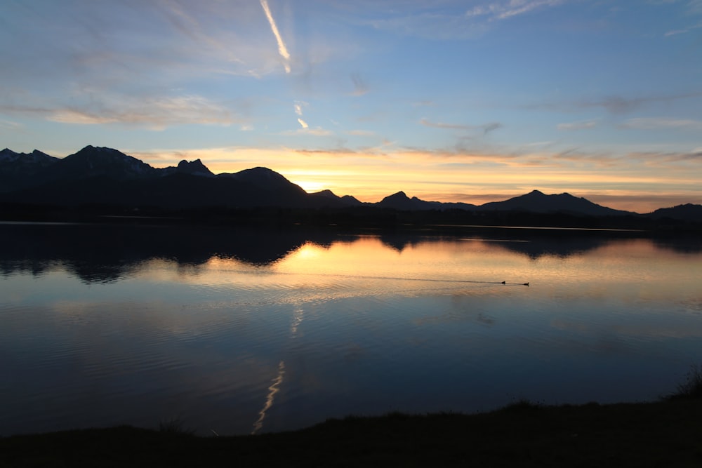 body of water near mountain under blue sky during daytime