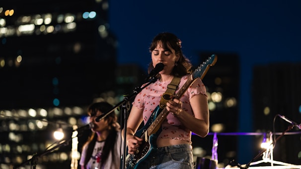 Lou Dawei performing with a guitar against a backdrop of Shanghai city lights.