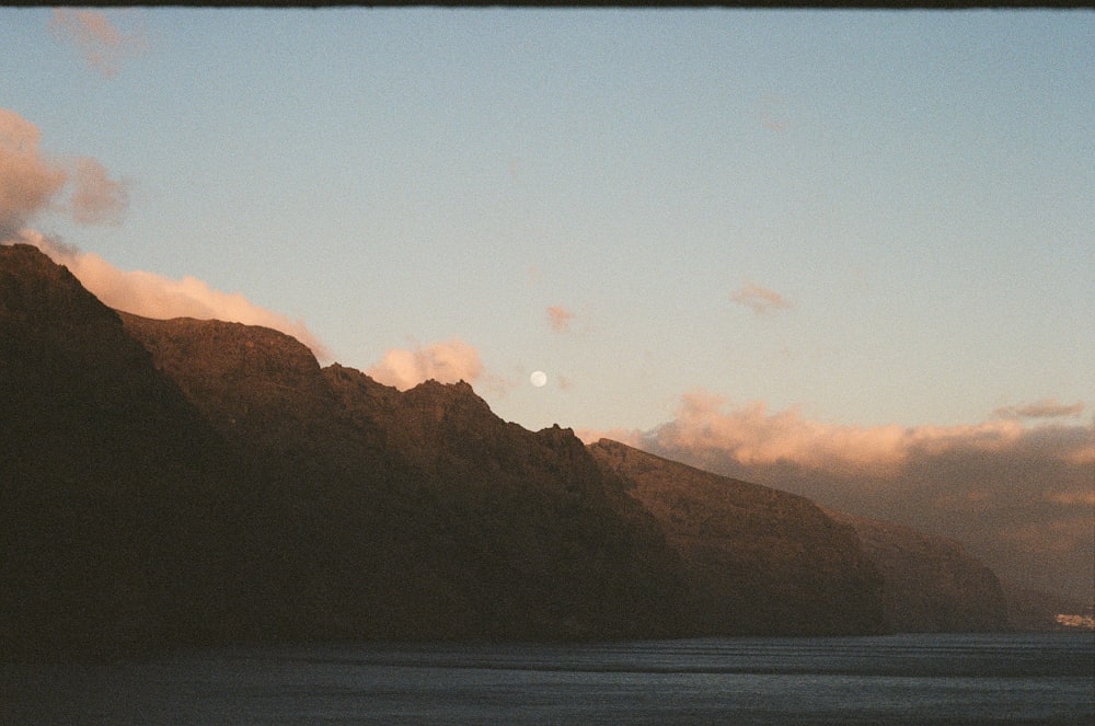 body of water near mountain during daytime