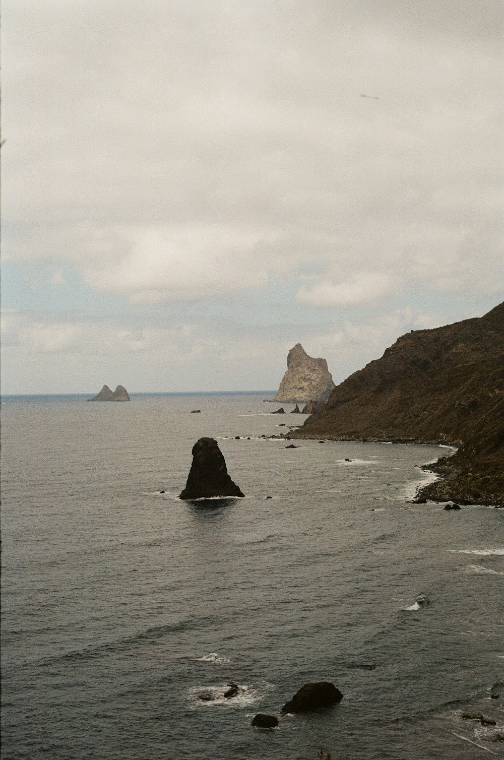 black rock formation on sea during daytime