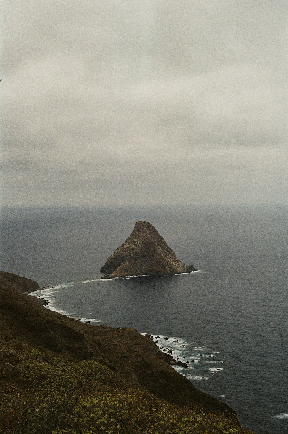 brown rock formation on sea under white clouds during daytime