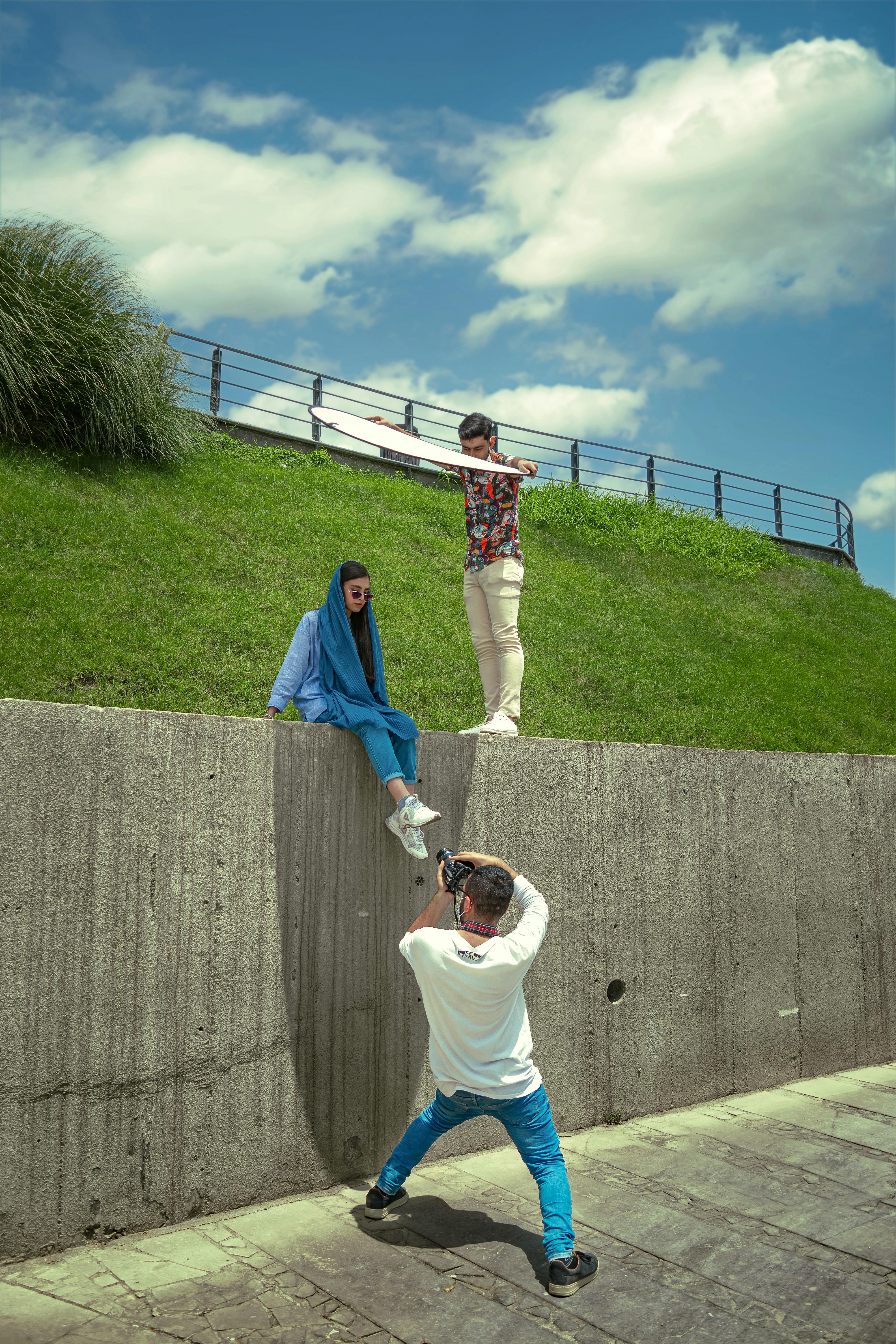 Uomo in maglietta bianca e pantaloni blu in piedi sul percorso di cemento grigio durante il giorno