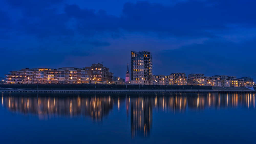 city skyline across body of water during night time