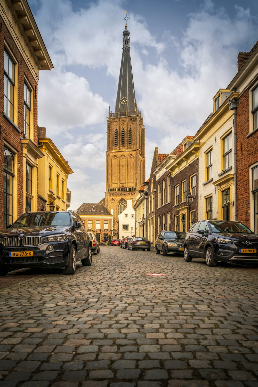 cars parked on the side of the road in between high rise buildings during daytime