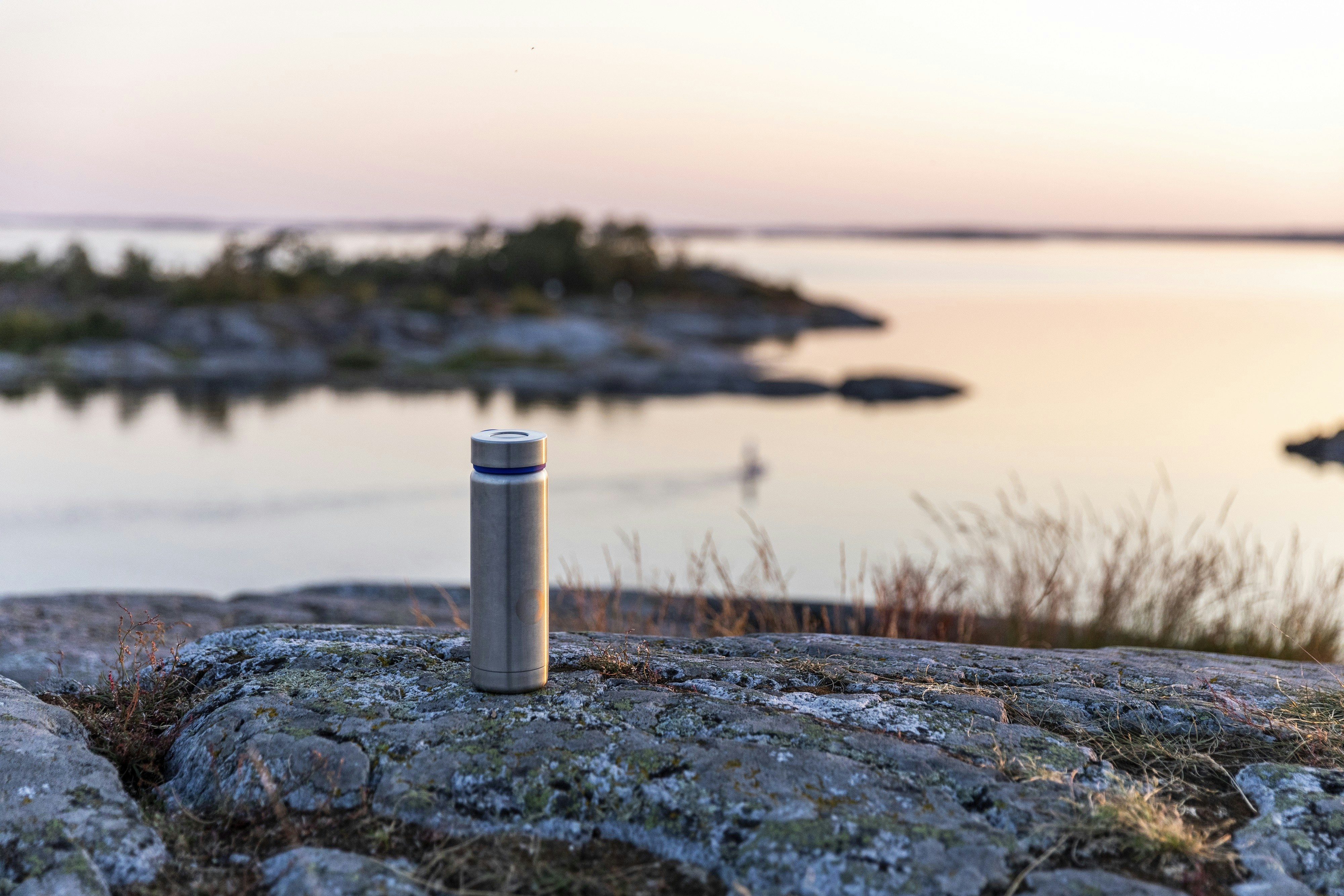 white and gray metal tube on brown grass near body of water during daytime