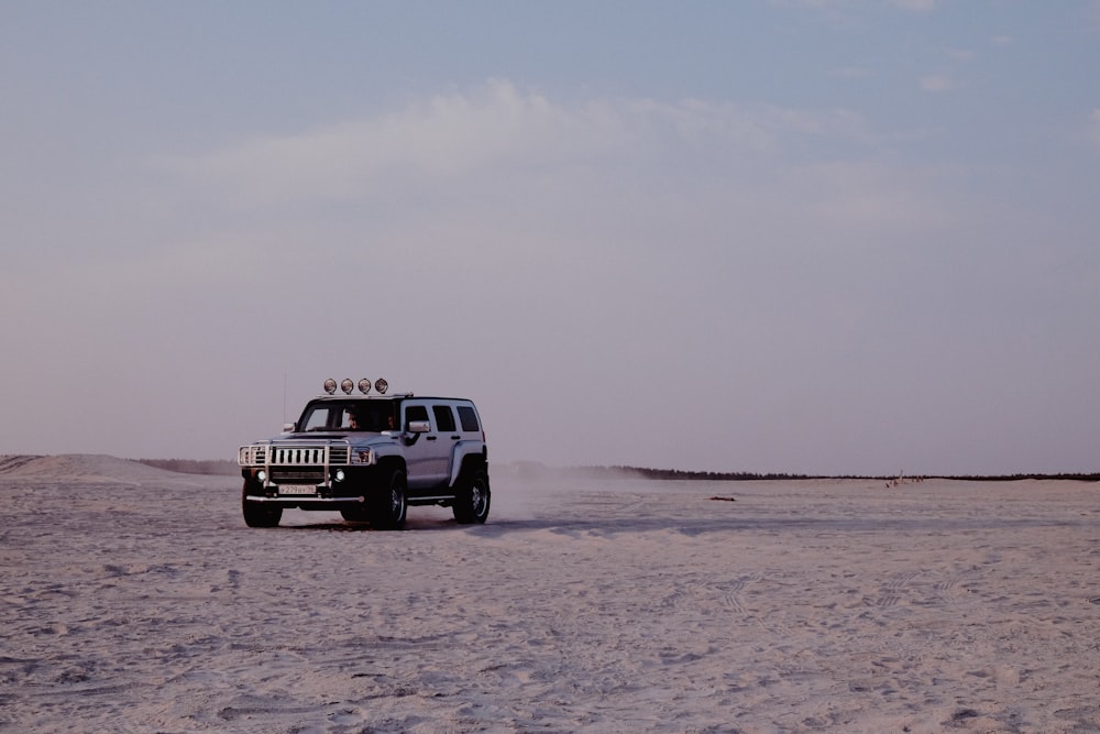 white and black jeep wrangler on brown sand under white sky during daytime
