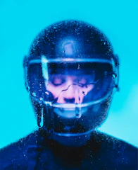Close-up of a helmet being cleaned inside a sleek automatic washing machine with blue and green lights.