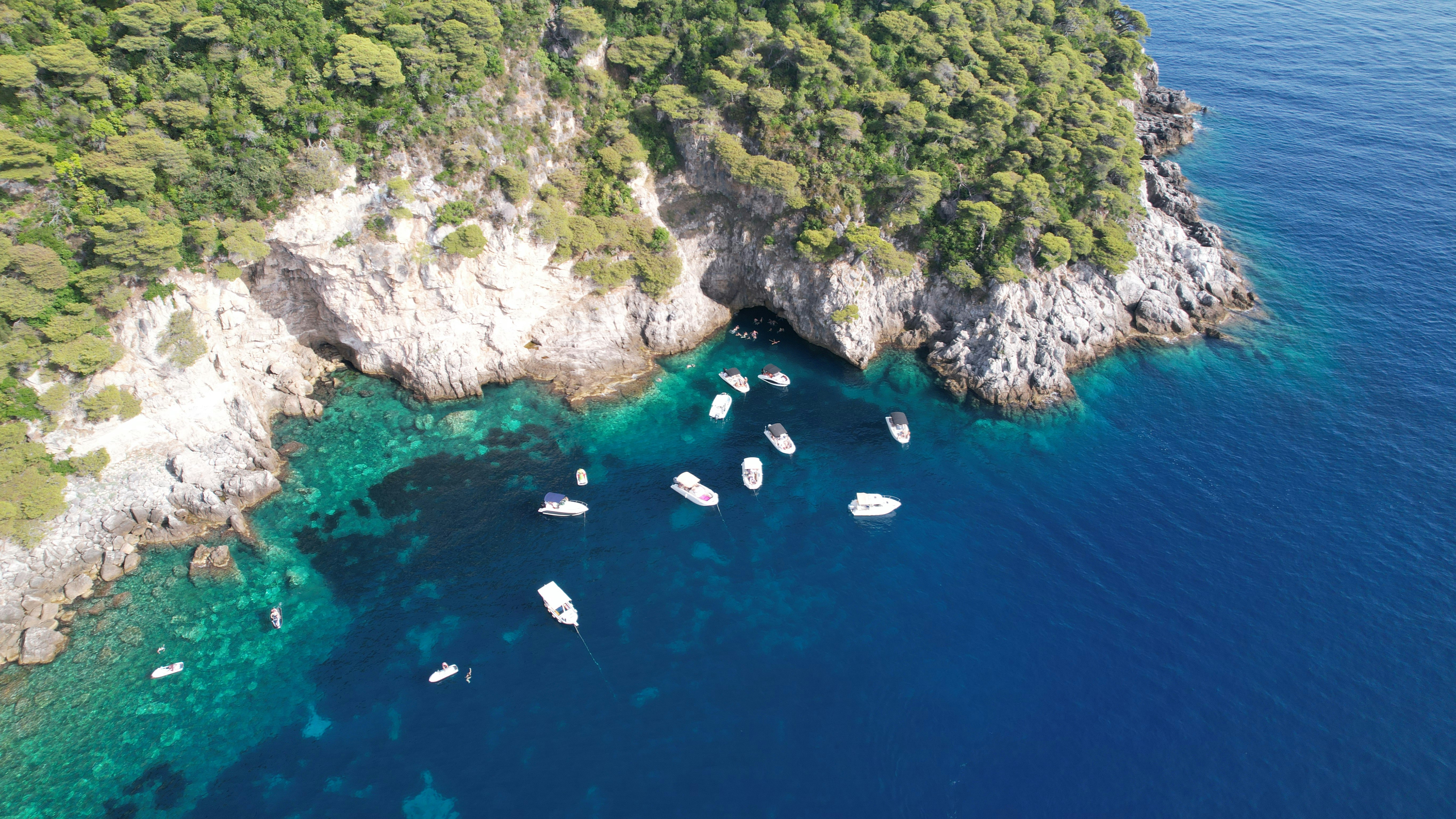 aerial view of boats on sea near green and brown mountain during daytime