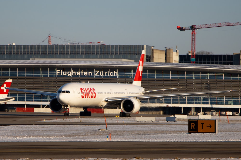 white and red passenger plane on airport during daytime