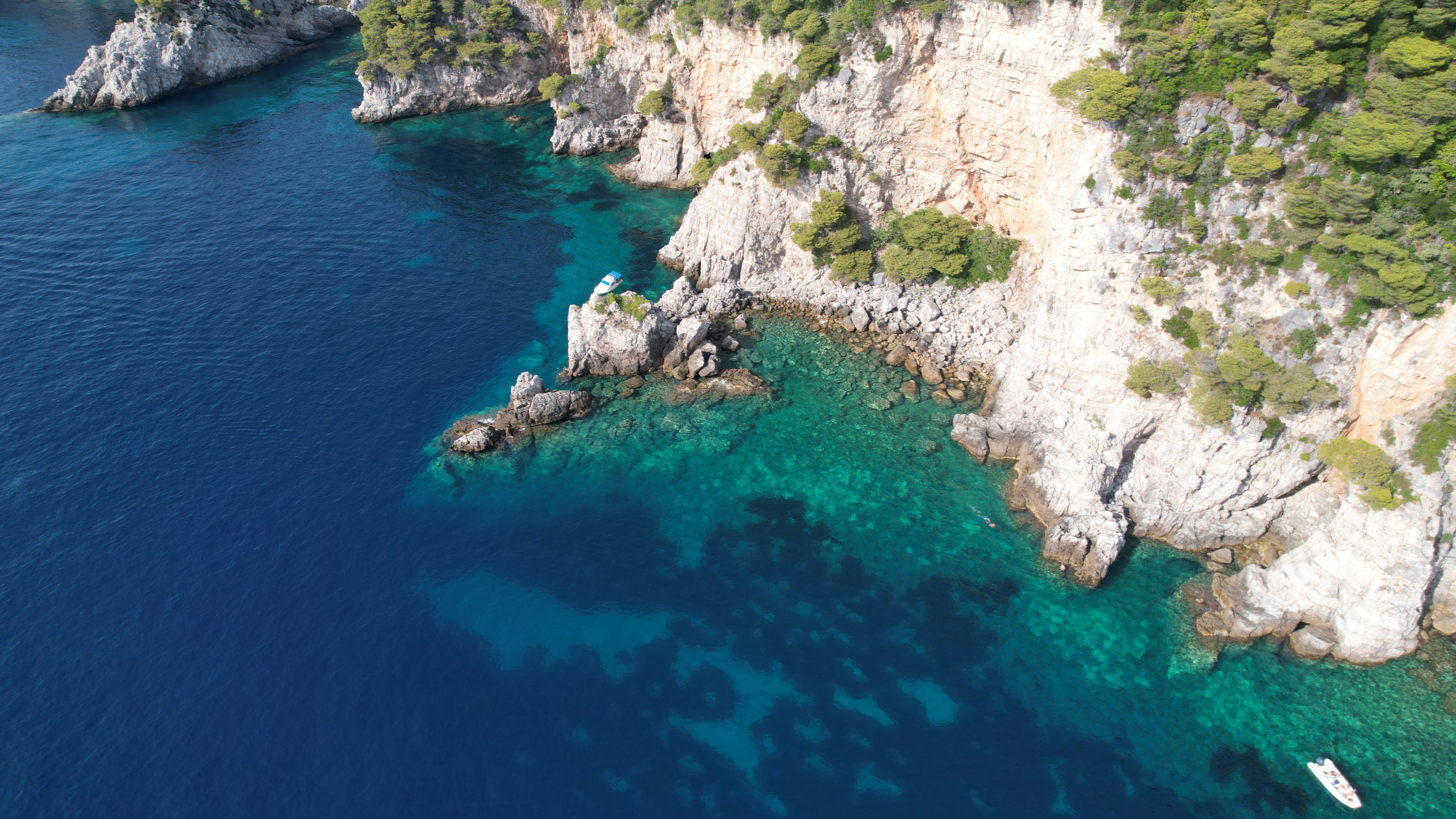 body of water near gray rocky mountain during daytime
