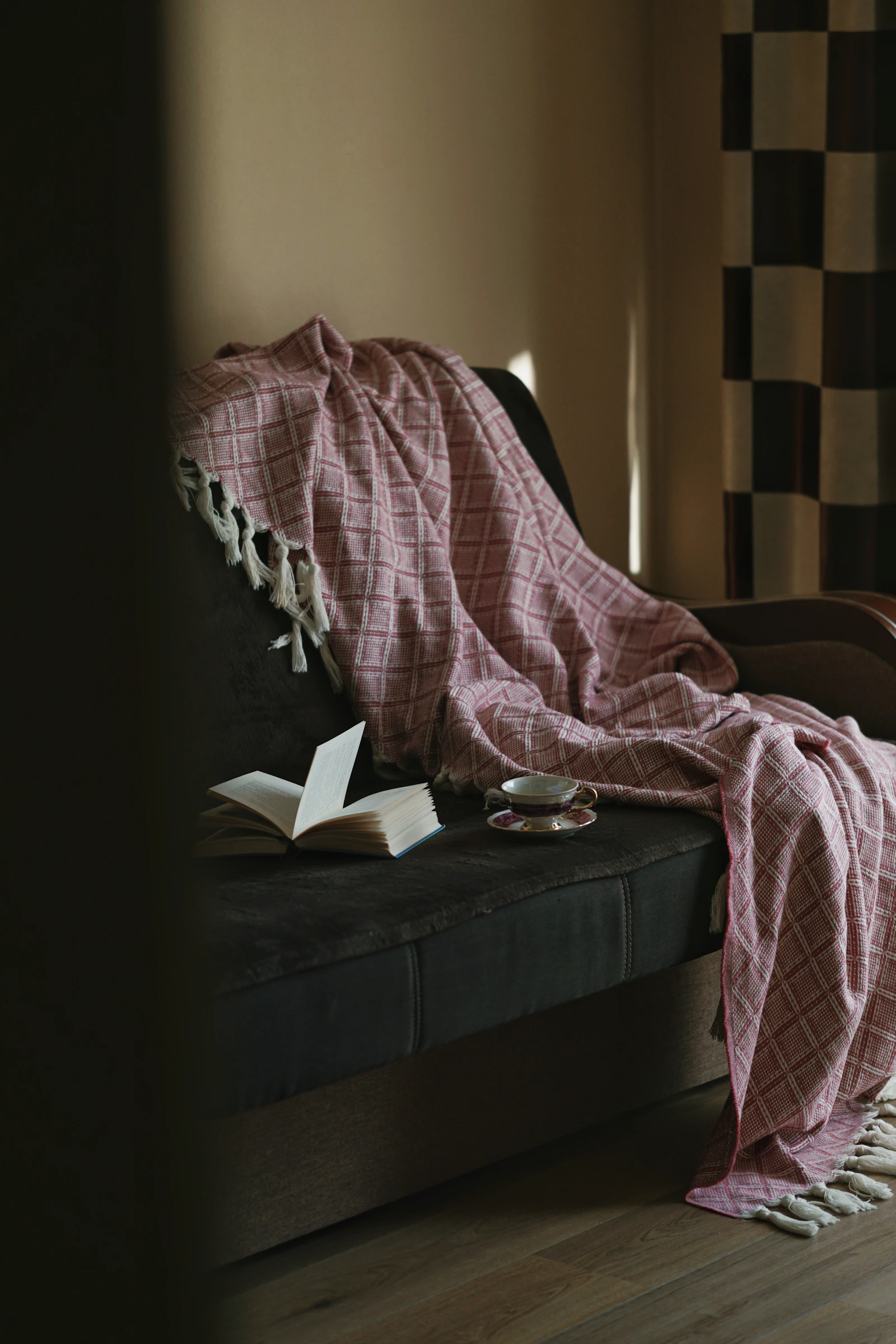 Fauteuil cosy avec plaid, livre ouvert et tasse de thé