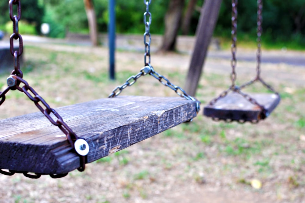 brown wooden swing on green grass field during daytime