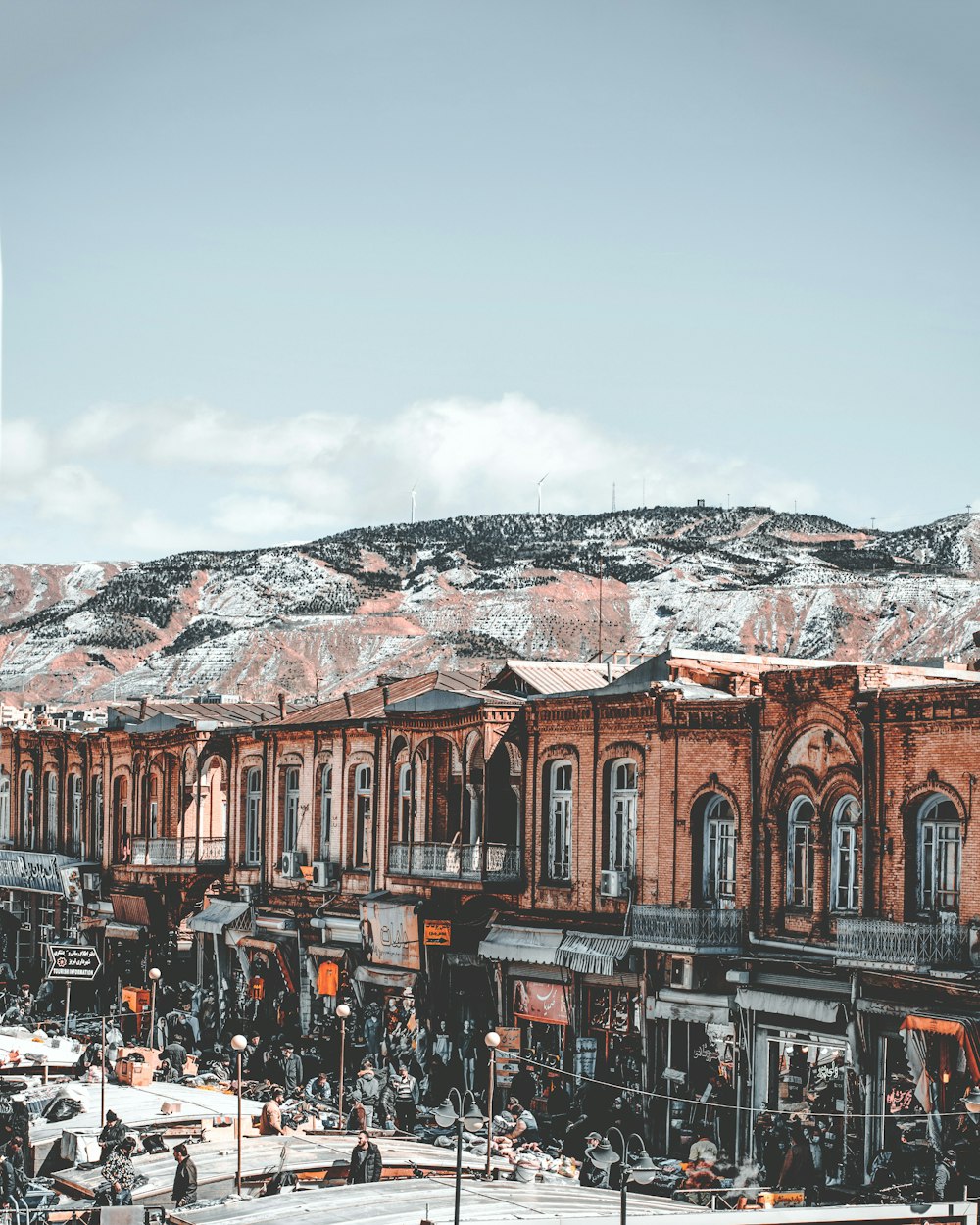 brown concrete building near snow covered mountain during daytime