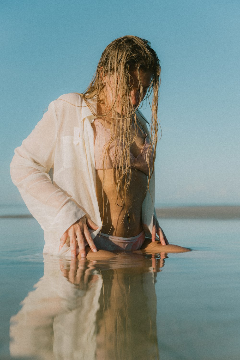 woman in white long sleeve shirt sitting on water during daytime