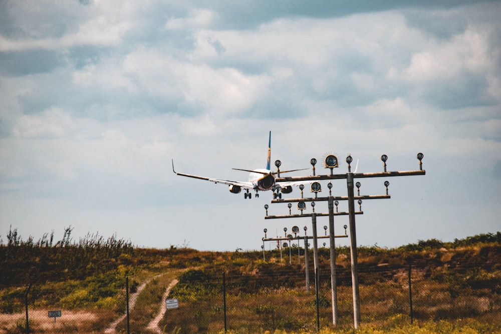 white and black airplane flying over green grass field during daytime