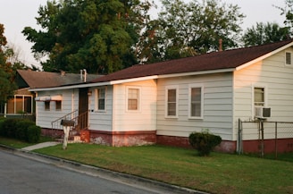 white and brown wooden house near green trees during daytime