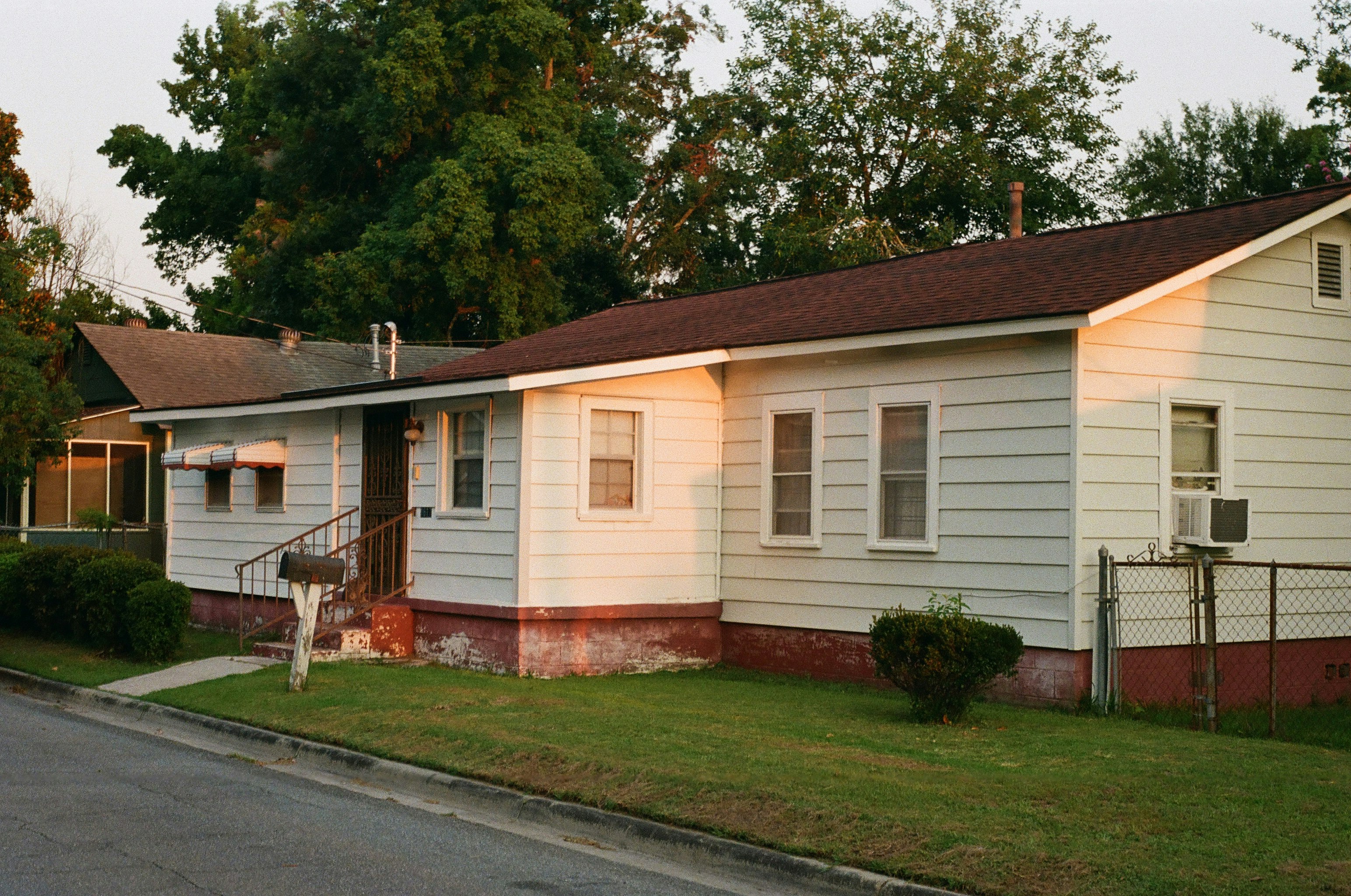 white and brown wooden house near green trees during daytime