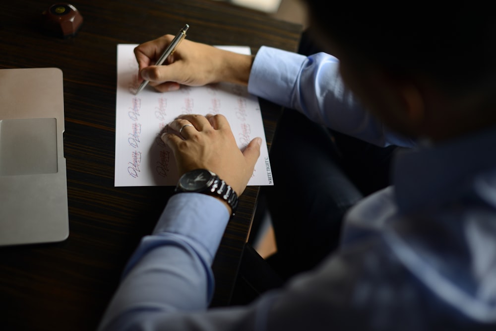 a man sitting at a desk writing on a piece of paper