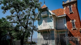 white and brown concrete house near green trees during daytime