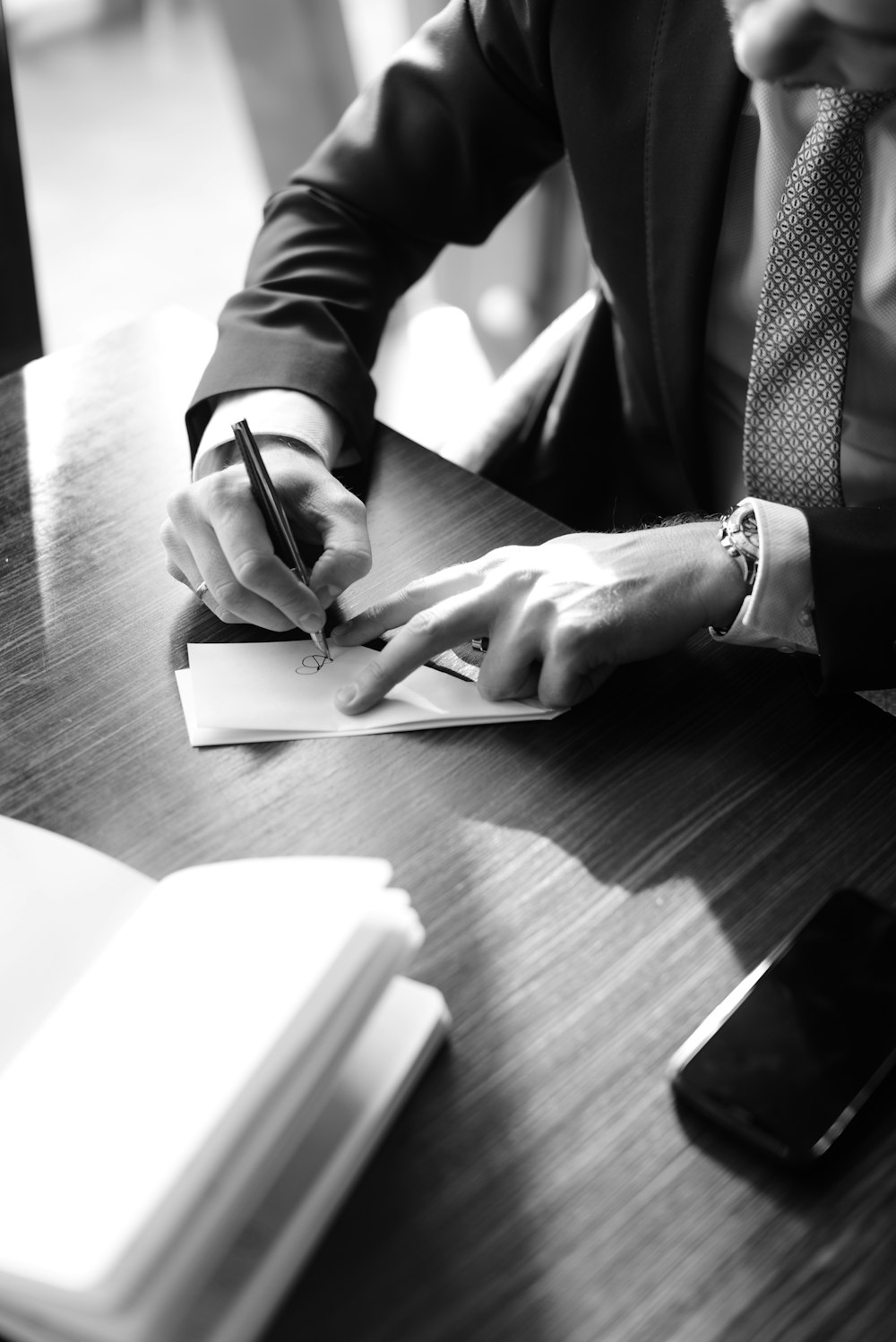 grayscale photo of person writing on notebook