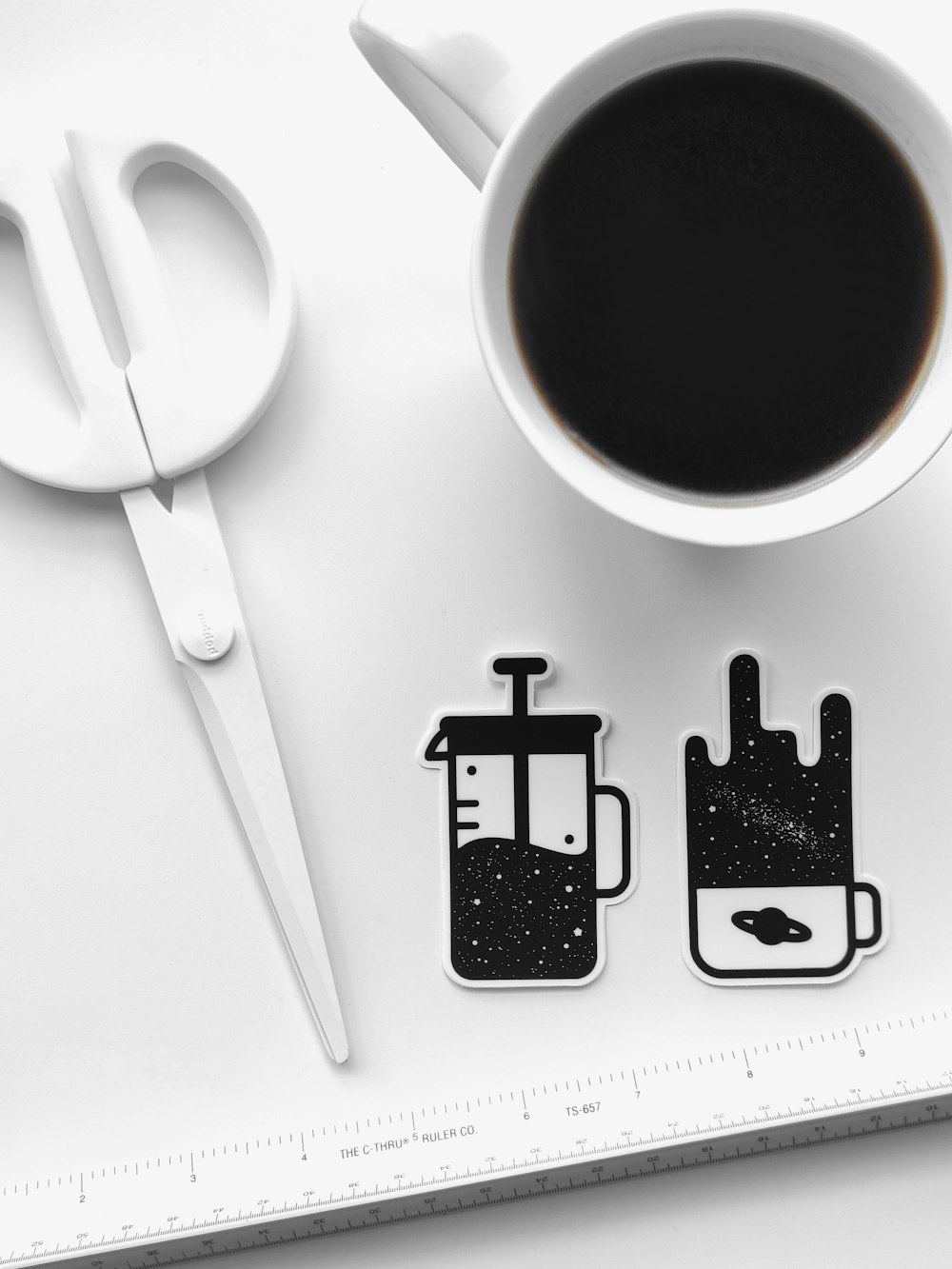 white ceramic mug with coffee beside stainless steel spoon and black square container