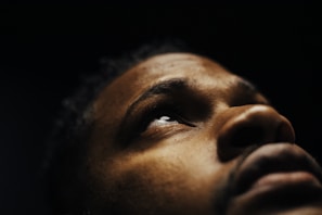 A dramatic close-up of a woman’s tear-streaked face under dim red lighting