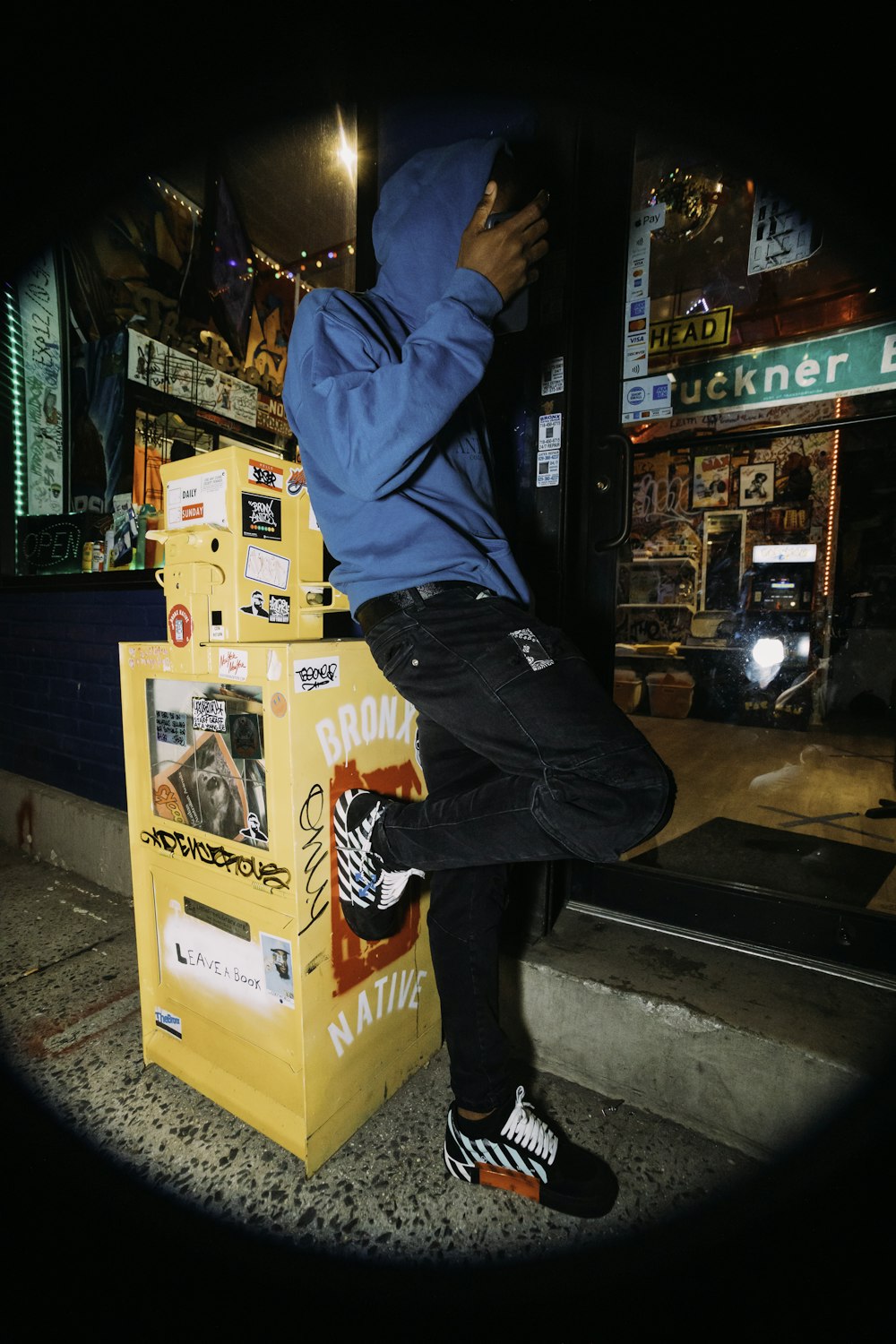 man in blue jacket and black denim jeans sitting on yellow box