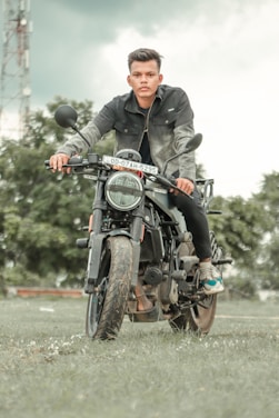 A friendly instructor guiding a learner on a motorcycle in a sunny outdoor setting.