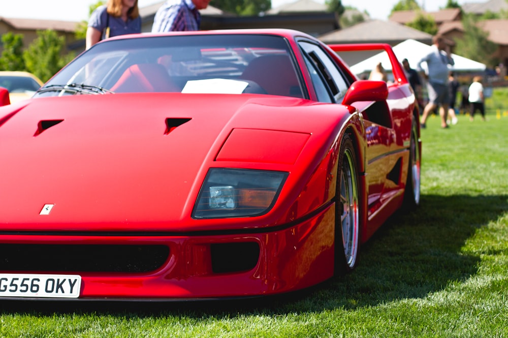 red ferrari 458 italia on green grass field during daytime