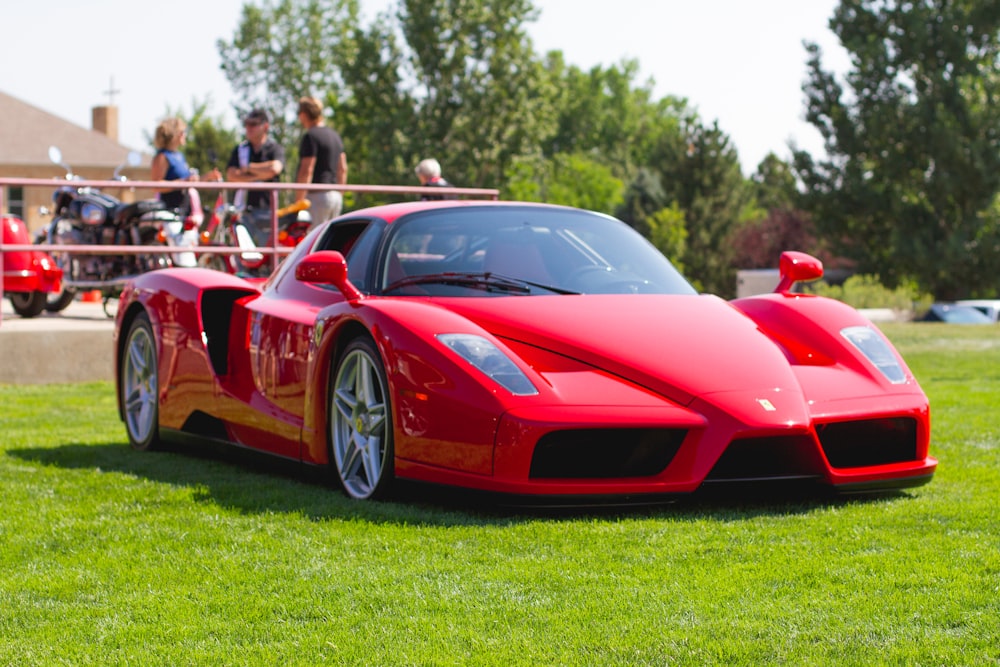 red ferrari 458 italia on green grass field during daytime